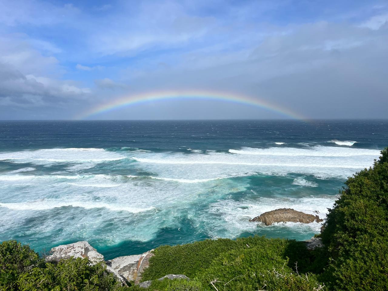 Dramatic Garden Route coastline beneath a rainbow
